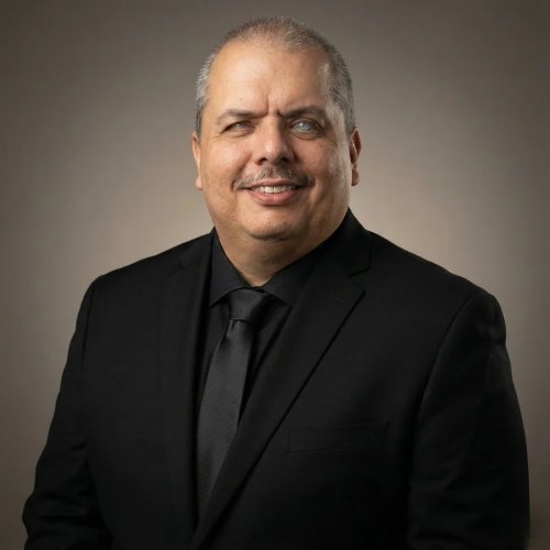 Guillermo Serafin, smiling, in a black suit and tie